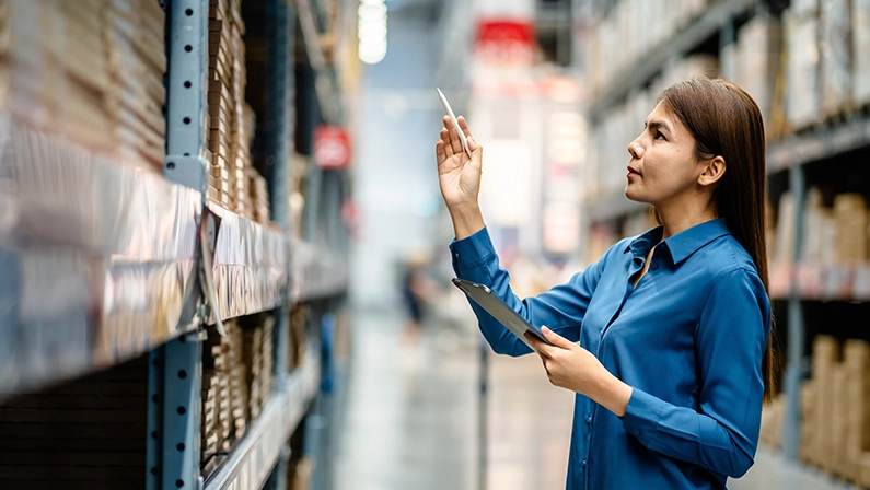 Women warehouse staff using digital tablets to check the stock inventory on shelves in large warehouses, a Smart warehouse management system, supply chain and logistic network technology concept.