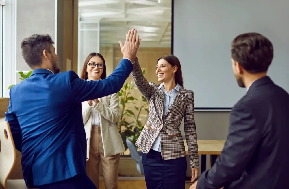 Professionals in business attire high-fiving each other after completing a job training program.