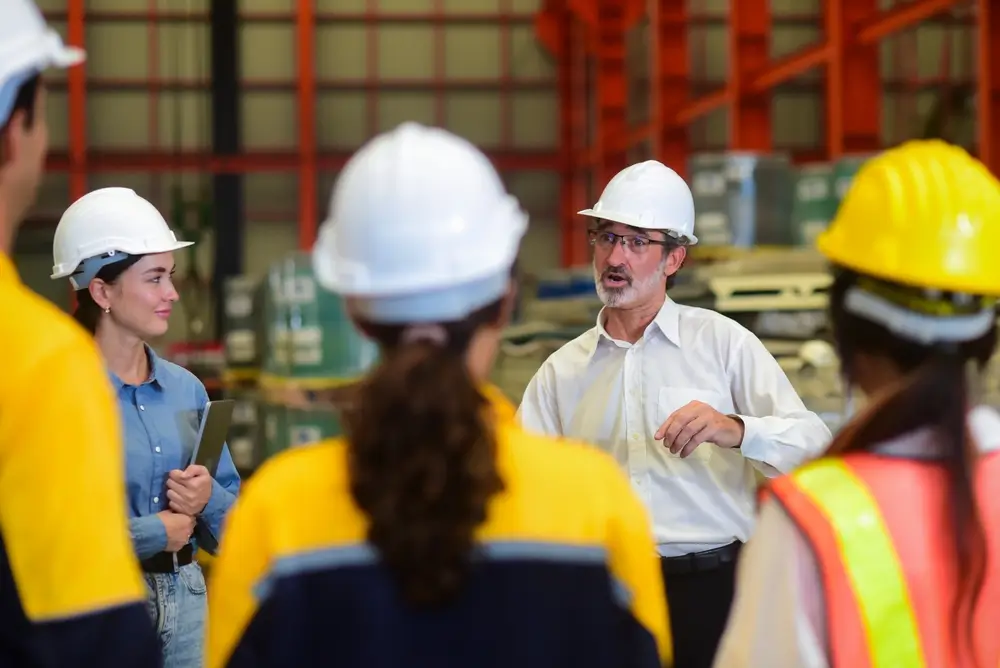 Workers in safety helmets participating in a hands-on job training session, listening to an instructor.