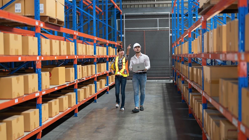 Warehouse team inspecting inventory with a laptop, focusing on supply chain risk assessment and operational efficiency.