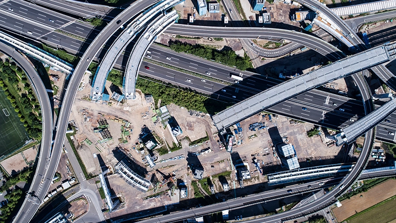 Aerial view of highway construction, representing large-scale infrastructure development and urban expansion projects.