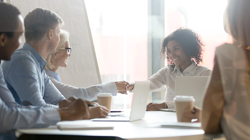 Smiling african female leader handshake partner client making commercial deal agreement at team meeting or group negotiations sitting at conference table shake hands thank for collaboration, respect