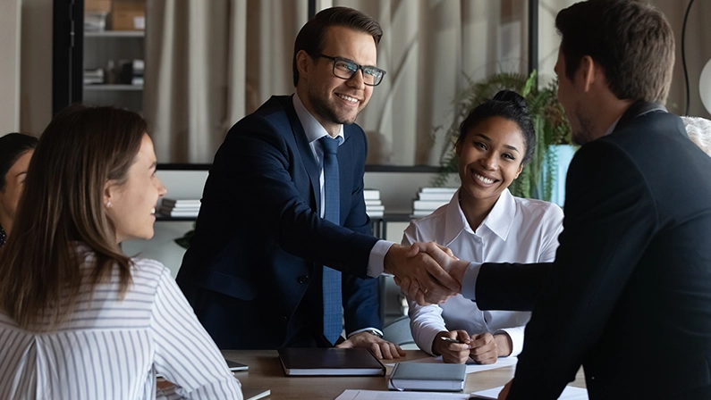 Nice to meet you in our team. Friendly man leader boss shake hand of new staff member welcome young male on job in corporate department. Professional businesspeople reached agreement on negotiations