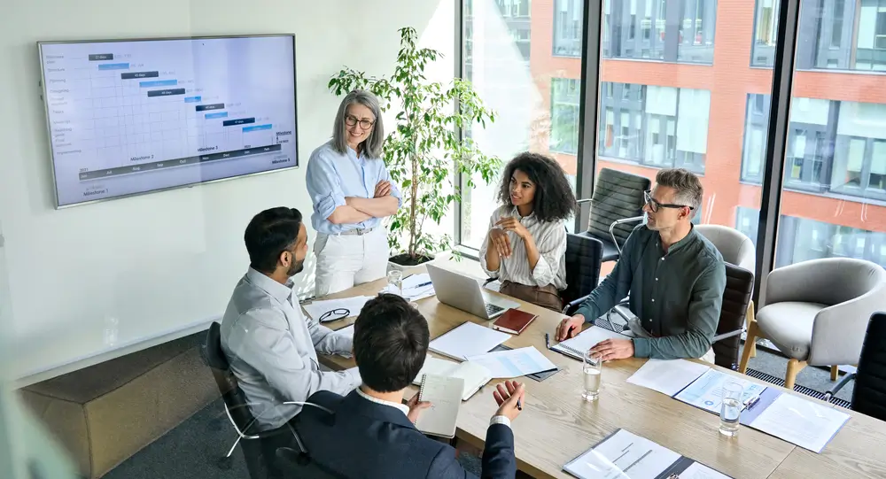 Business team analyzing a project timeline on a screen, discussing winning market strategies for business growth.