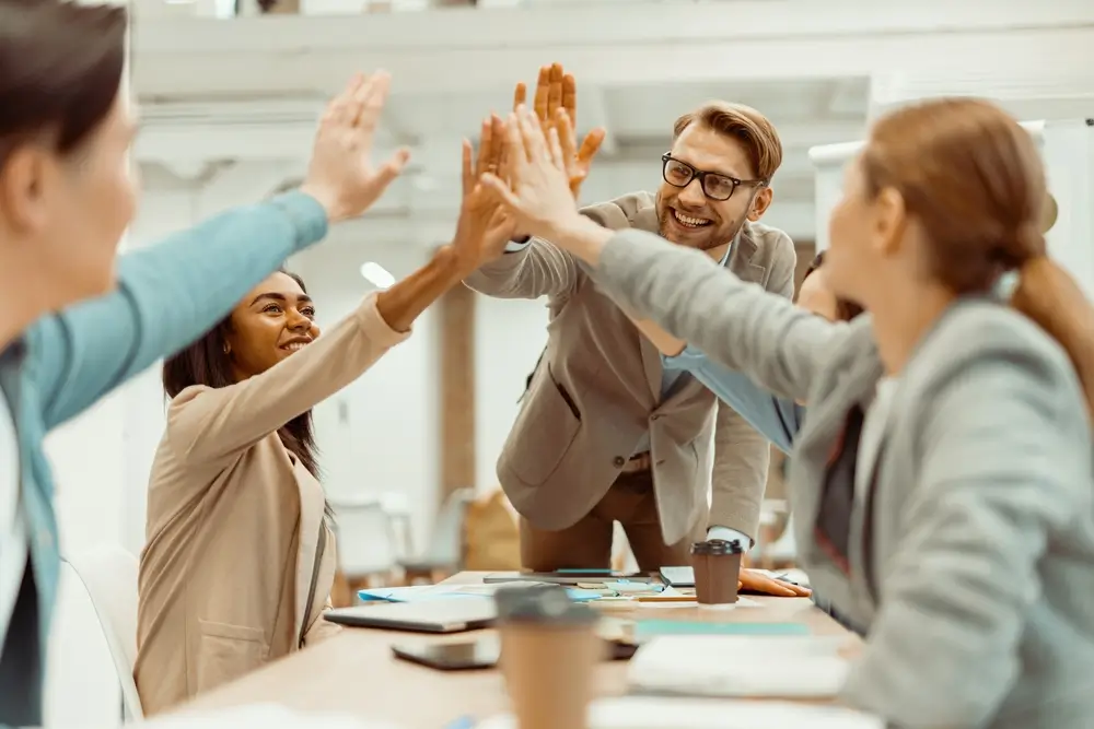 Team celebrating success with a high-five, symbolizing teamwork and business development strategies for growth.