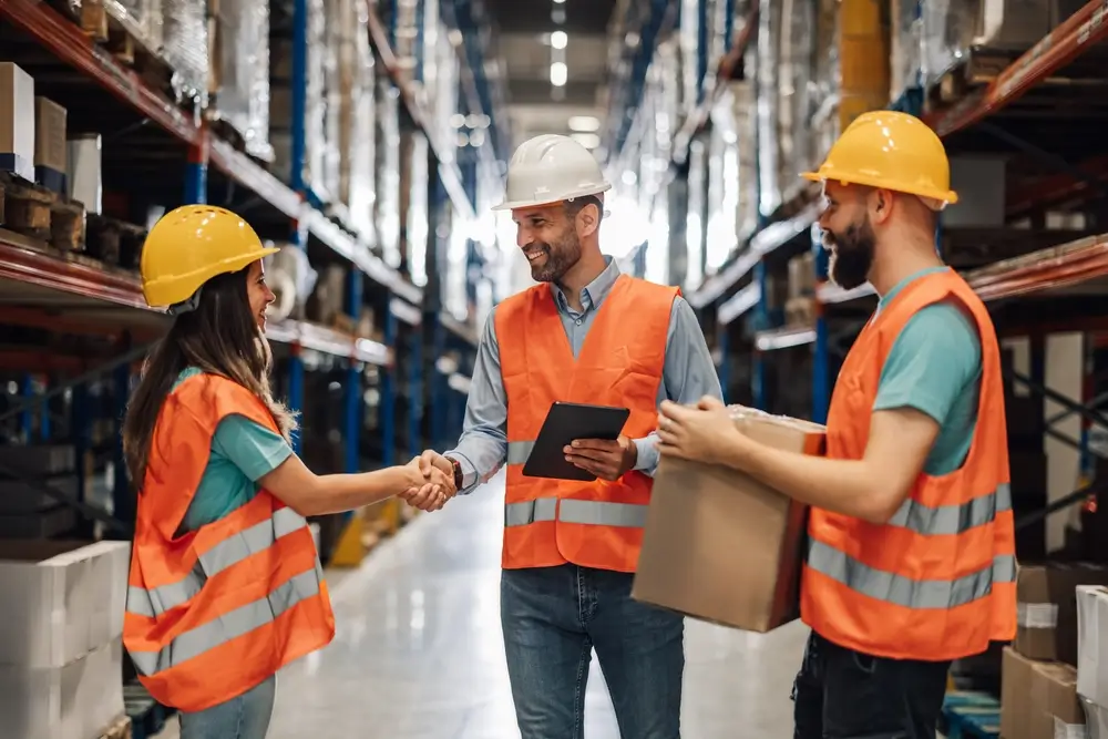 In a dynamic warehouse, a manager and employee shake hands, marking a successful partnership. 