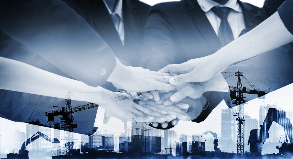 A composite image of business professionals joining hands in unity, overlaid with construction cranes and city infrastructure, symbolizing the impact of workforce development.