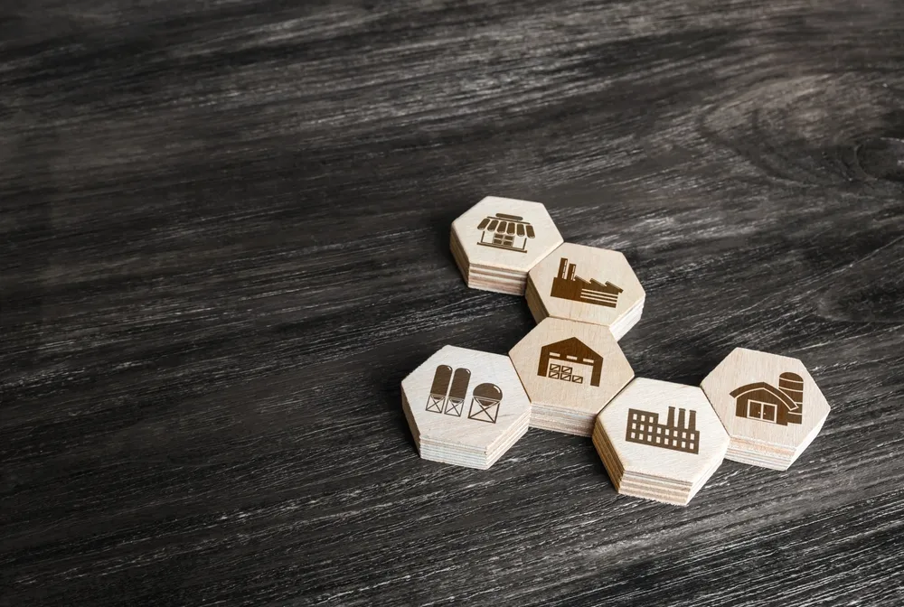 Wooden hexagonal blocks with industry icons symbolize cluster development, showcasing interconnected sectors on a dark wooden surface.