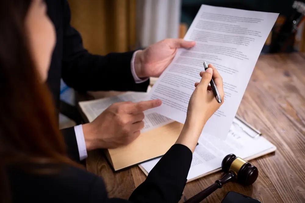 A lawyer and client discussing government contracting terms, holding a contract while pointing at key legal clauses.