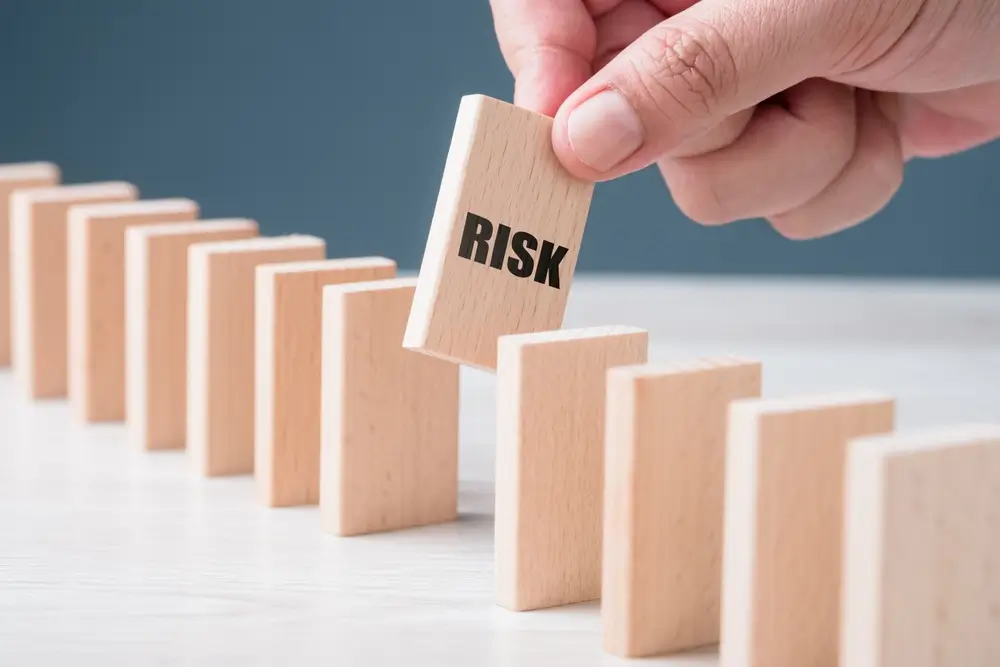 Hand putting a wooden piece between the others of the domino and risk to make it fall down