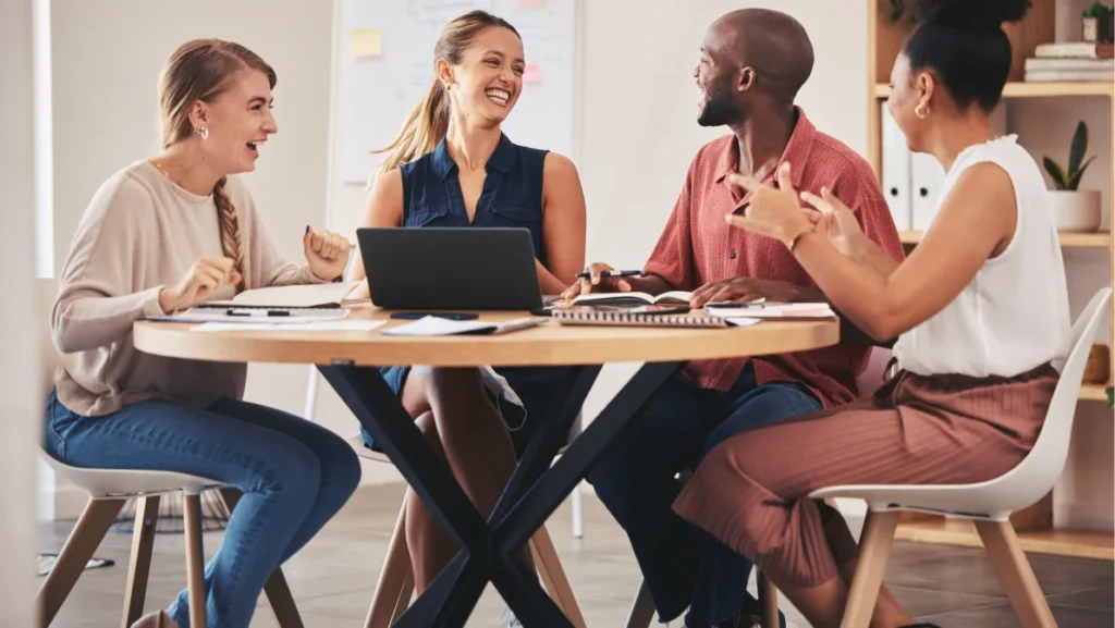 A collaborative team discusses innovative job creation strategies in a relaxed, creative office environment.