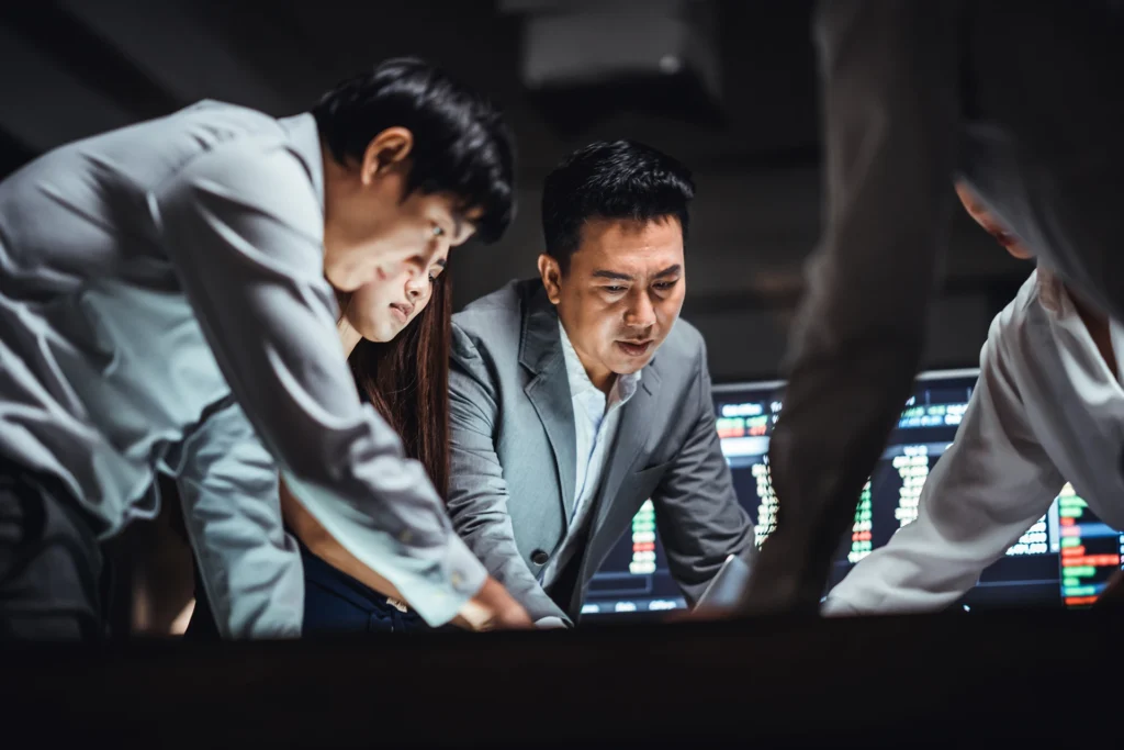 Group of Asian business financial team in strategic meeting, work late night shift in office. Business strategy analysis, stock market trading, corporate company, colleague coworker teamwork concept