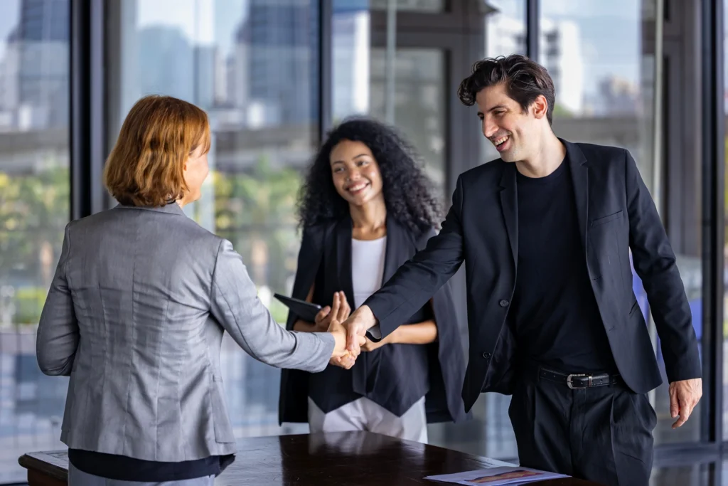 Team of diversity business people having agreement and handshake deal over new strategic strategy project on investment real estate with recognition and applause from other colleague for partnership