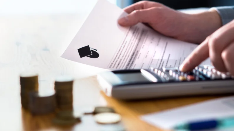 Man counting college savings fund, tuition fee or student loan with calculator. Education price and expenses concept. Money and papers on table. Calculating budget and planning finance.
