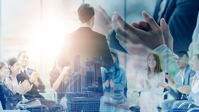 A leader is applauded by a team, representing success despite labor shortages, with a cityscape overlay symbolizing growth.