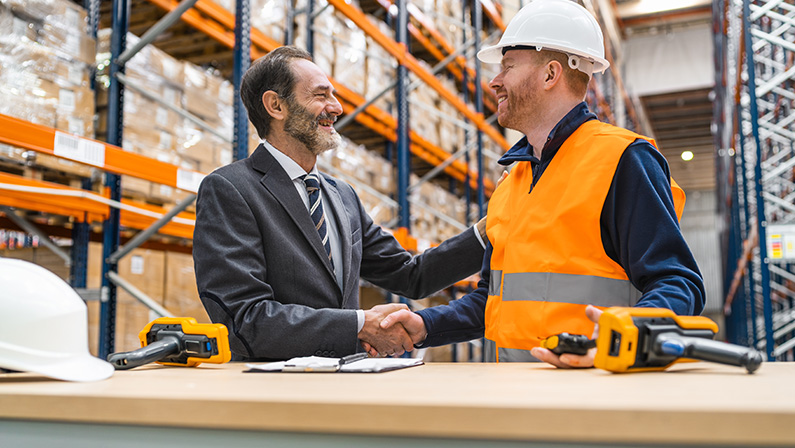 Manager and worker shaking hands in warehouse, logistics, delivery, distribution, supply chain, teamwork, partnership, success